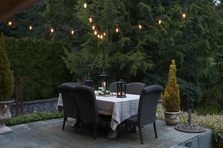 how to make your backyard special with outdoor lighting, beautiful outdoor patio setting with string lights and dining table