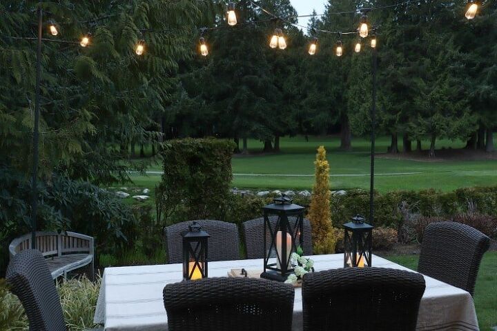how to make your backyard special with outdoor lighting, outdoor dining table with string lights overhead
