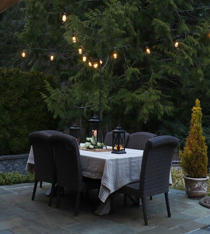 how to make your backyard special with outdoor lighting, outdoor dining table with overhead string lights adds the perfect amount of mood lighting