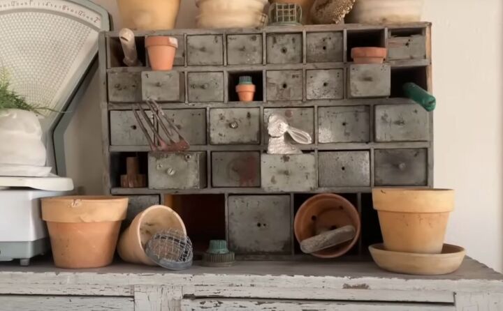 Apothecary cabinet with terra cotta pots, flower frogs, and vintage gardening tools